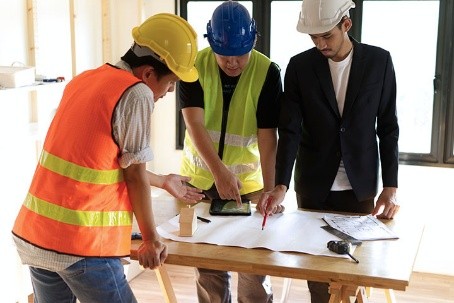 Three construction professionals reviewing building plans on a table